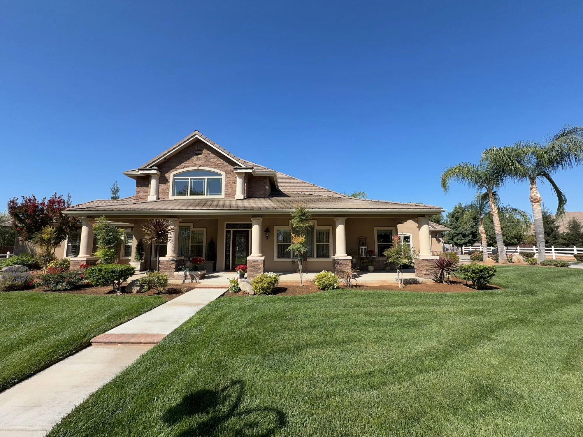 Two-story home with a stone gable and covered porch photographed in daylight, with Halo roofline lighting installed but nearly invisible
