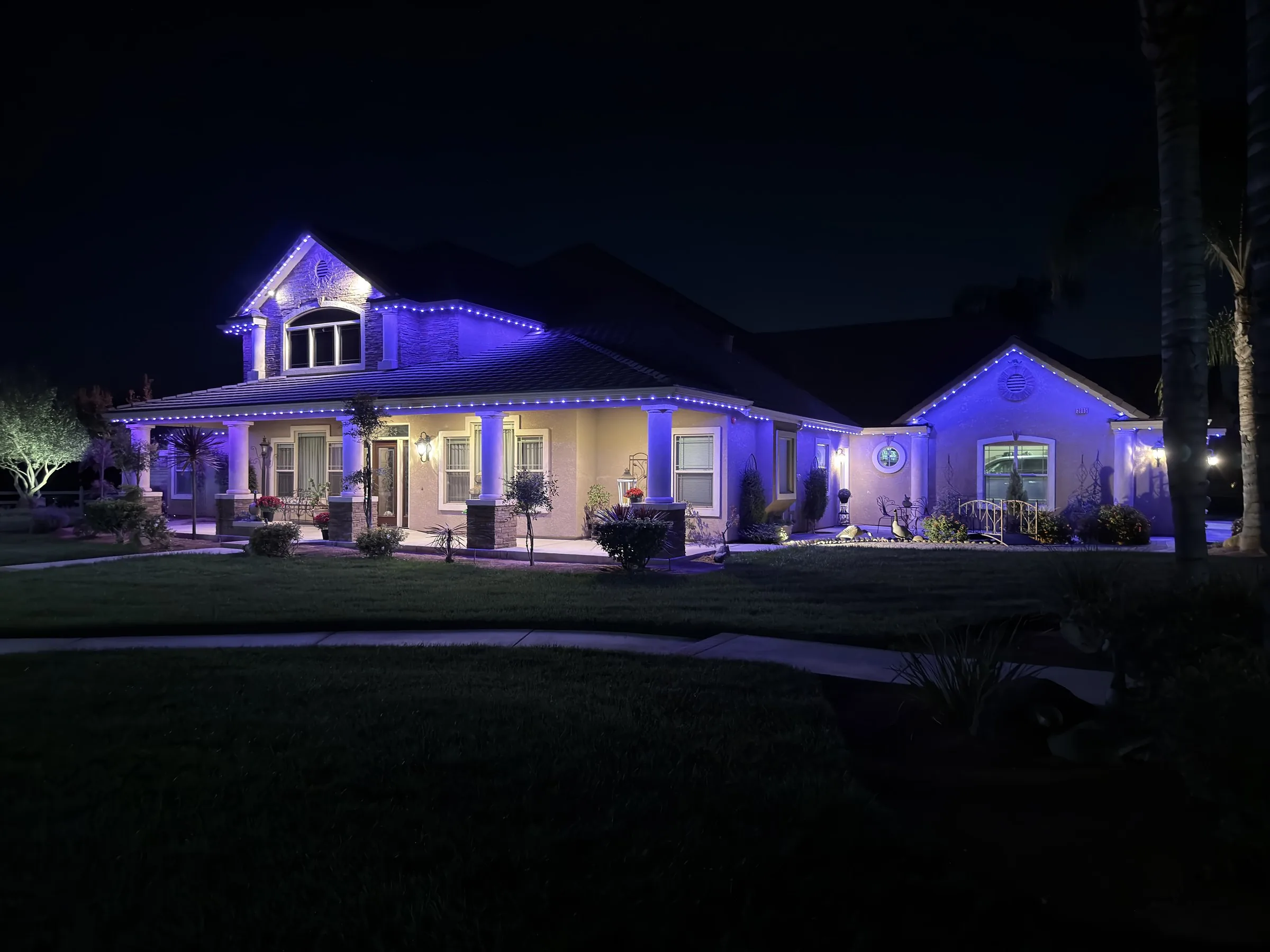 The same home at night with Halo roofline lighting in violet