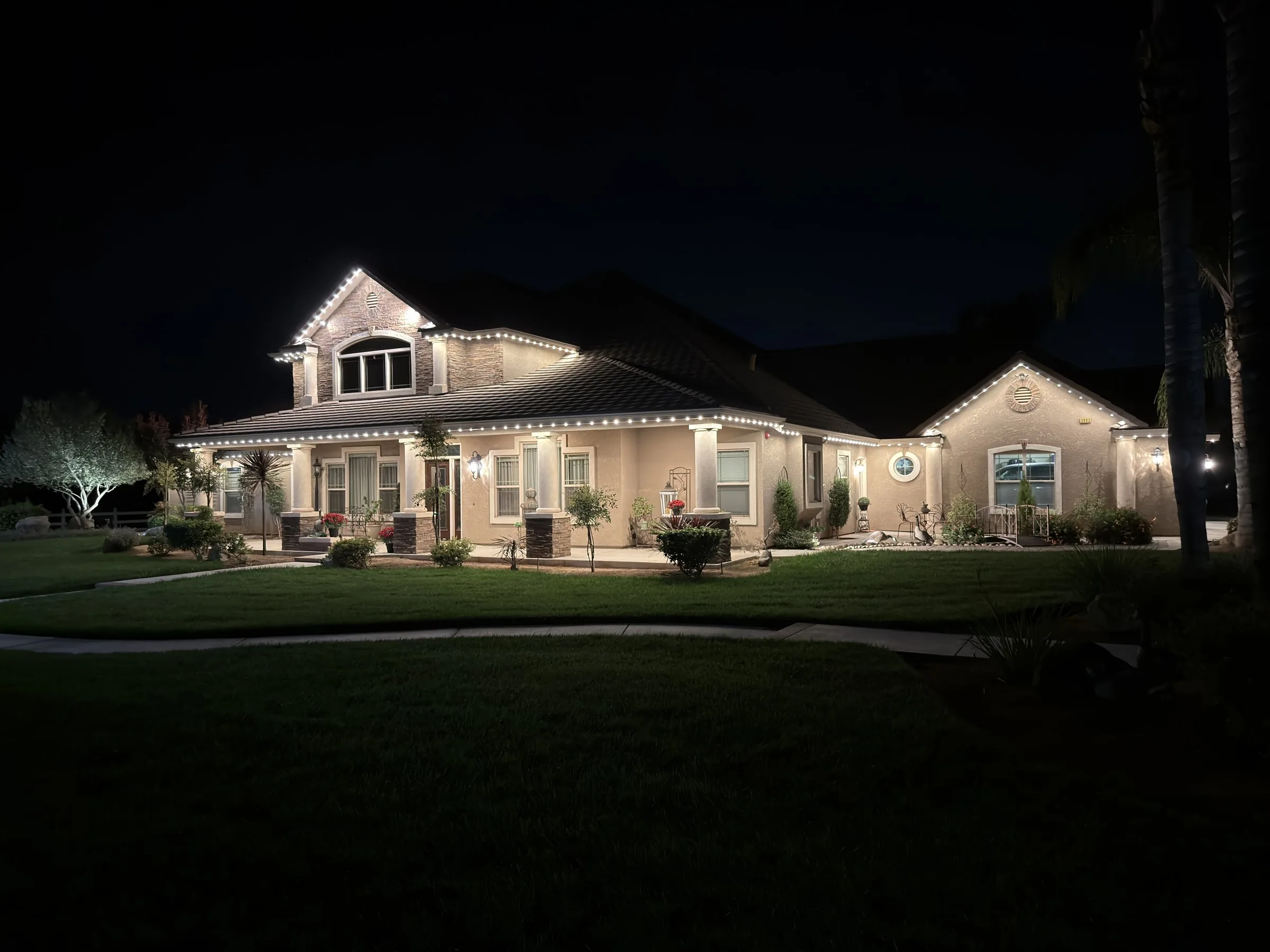 The same home at night with Halo roofline lighting in warm white tracing the gables and porch roof