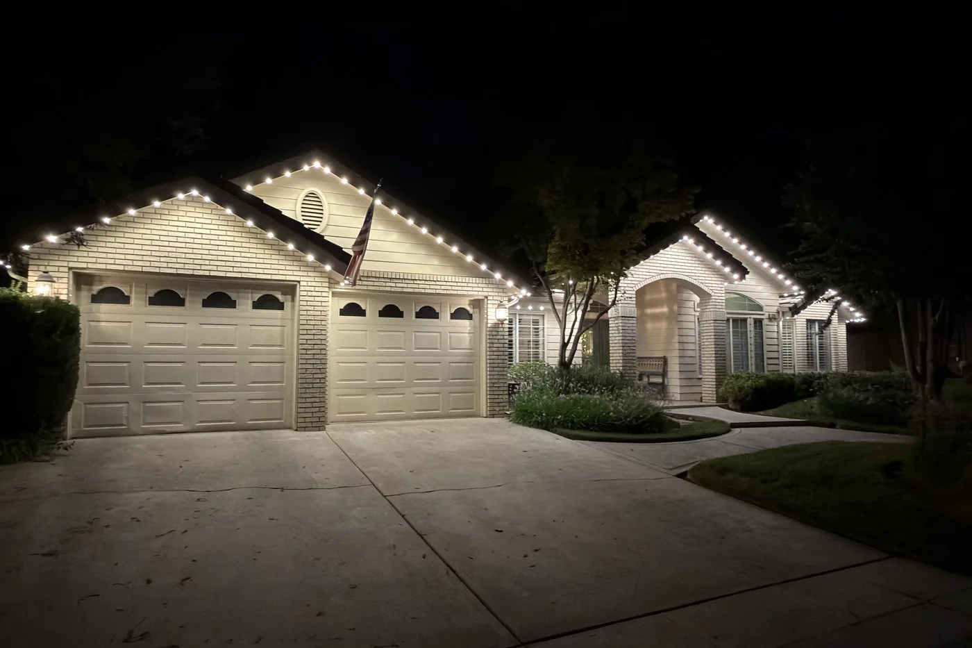 Unedited phone photo of a Clovis home at night with warm white permanent roofline lighting